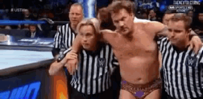 a man is being helped out of a wrestling ring by referees .