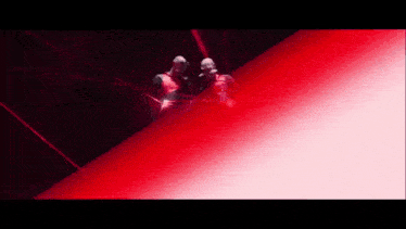 a couple of people standing next to each other in front of a red light beam .