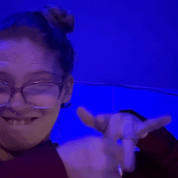 a woman wearing glasses and a bun is smiling and making a funny face .