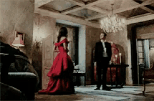 a woman in a red dress and a man in a suit are standing in a living room .