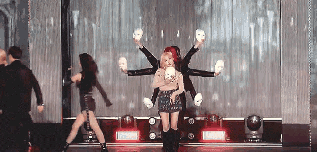 a group of people are dancing on a stage with masks
