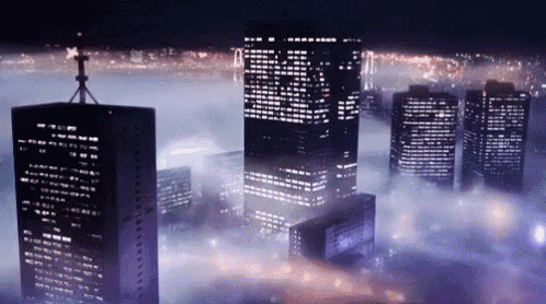 an aerial view of a city at night with a foggy sky