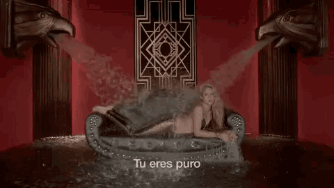 a woman is laying on a couch in a room with water coming out of it and the words `` tu eres puro '' .