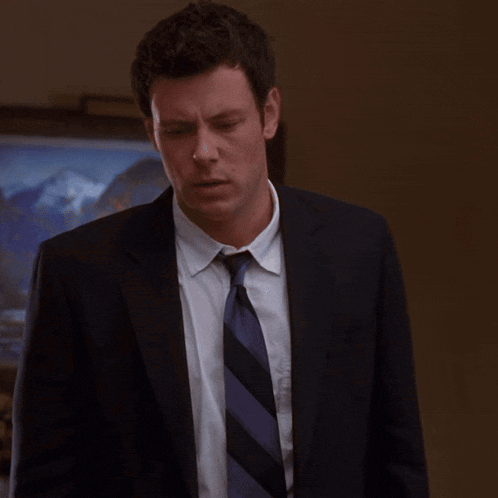 a man in a suit and tie looks down at something