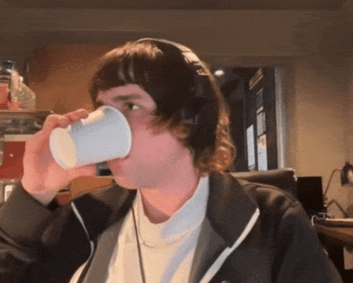 a man wearing headphones drinks from a cup