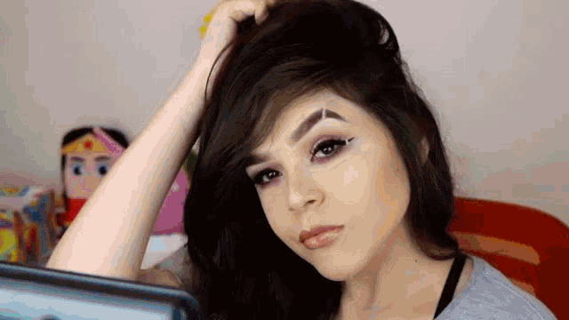 a woman with long hair is looking at herself in a mirror while holding her hair .