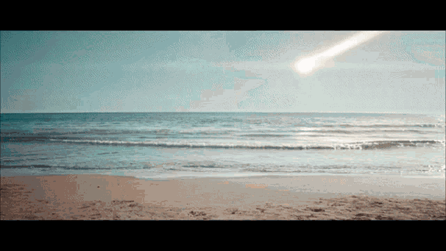 a shooting star is visible in the sky above a beach