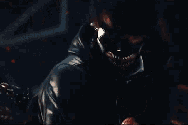 a man wearing a mask and a leather jacket is holding a knife .