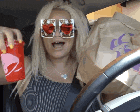a woman in a car holding a taco bell bag