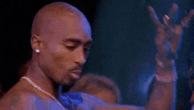 tupac shakur is making a peace sign with his hands .