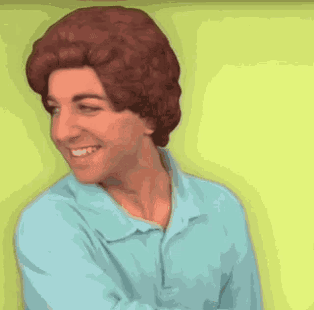 a man wearing a blue shirt and a wig smiles