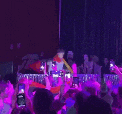 a crowd of people are taking pictures of a man on stage with their cell phones
