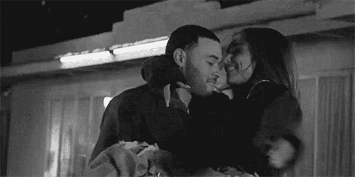 a black and white photo of a man and a woman hugging each other .