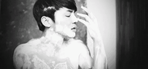 a black and white photo of a man shaving his face .