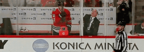 a hockey game is being played in front of a konica minolta advertisement