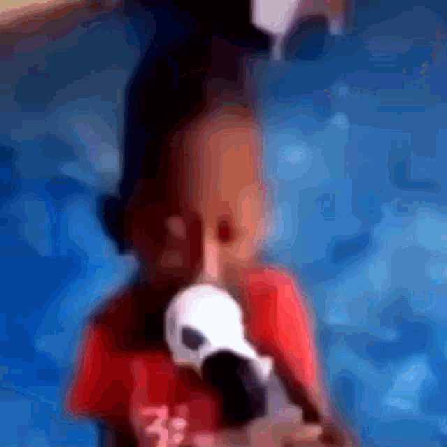 a blurry picture of a person holding a microphone and wearing a red shirt with the letter k on it