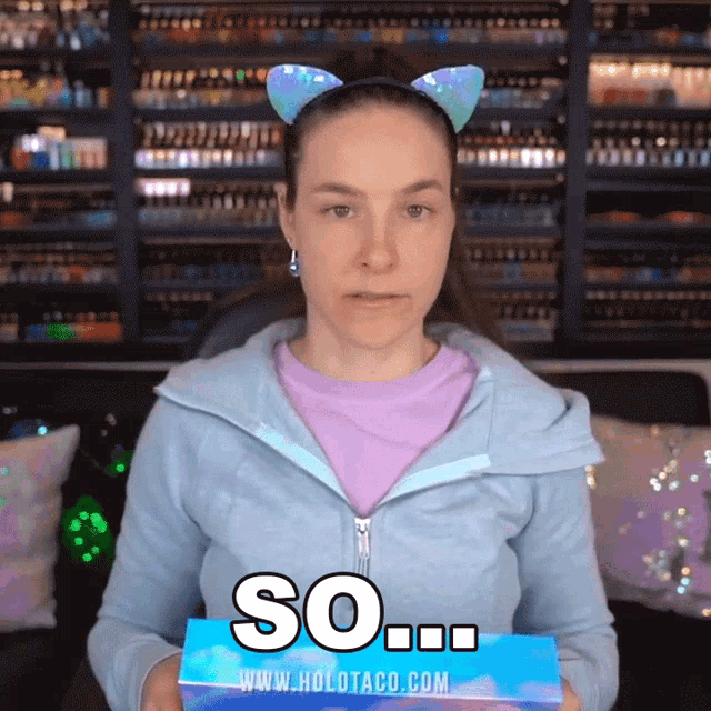 a woman wearing cat ears holds a box that says so
