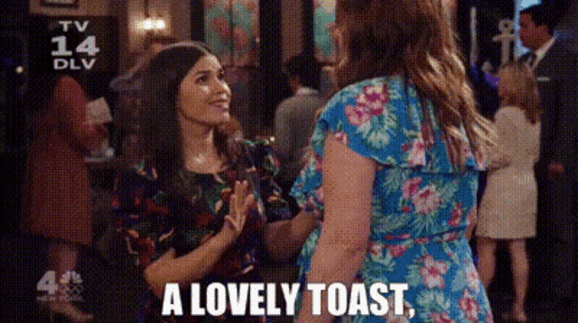 two women are standing next to each other in a crowd and one of them is saying a lovely toast .