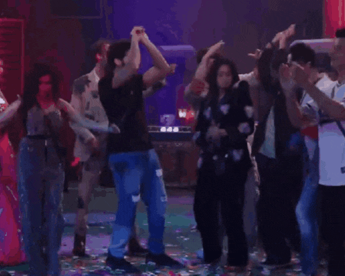 a group of people are dancing on a stage in a dark room .