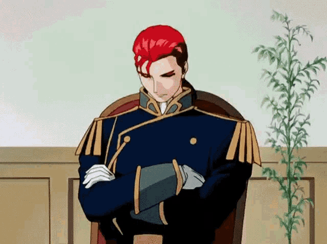 a man with red hair is sitting with his arms crossed in front of a plant .