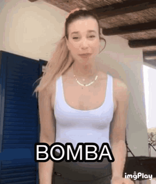 a woman in a white tank top has the word bomba written on her chest