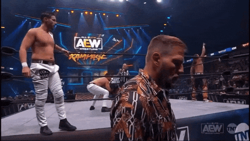 a group of wrestlers are standing in a ring with the aew logo on the wall behind them
