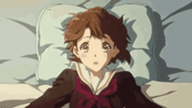a girl in a school uniform is laying on a bed with a blue pillow .