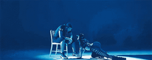 a man is sitting in a chair next to a woman who is kneeling down on a stage .