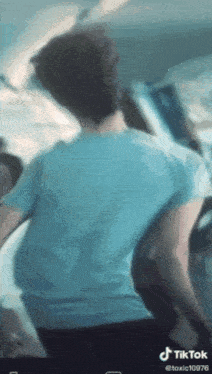 a man in a blue shirt is standing in a crowd on a train .