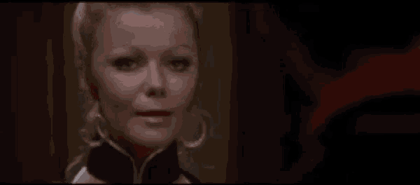 a close up of a woman wearing hoop earrings looking at the camera in a dark room .