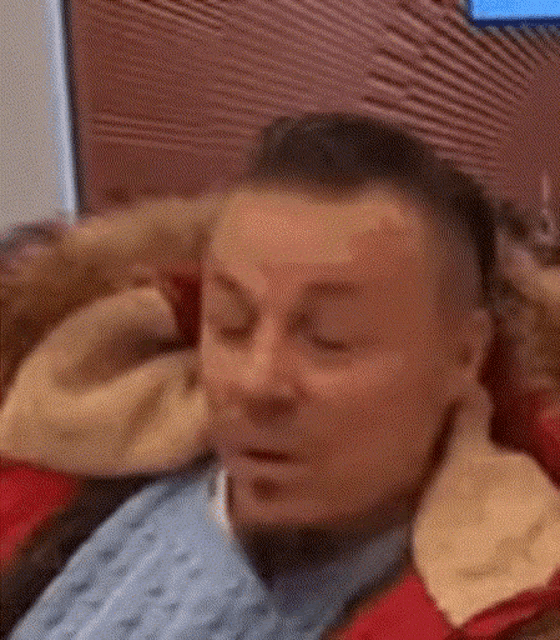 a man is sitting in a chair with his eyes closed and his head resting on a pillow .