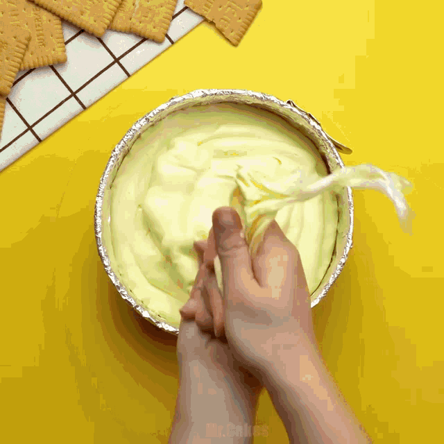 a person is making a cheesecake in a tin foil pan with the word mr. bakes on the bottom