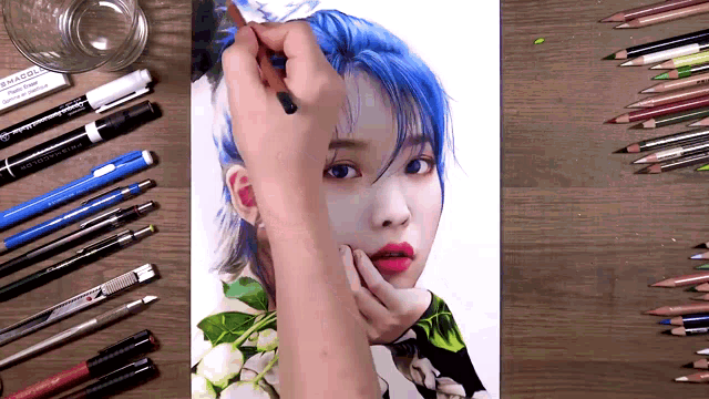 a drawing of a woman with blue hair is surrounded by colored pencils and pens