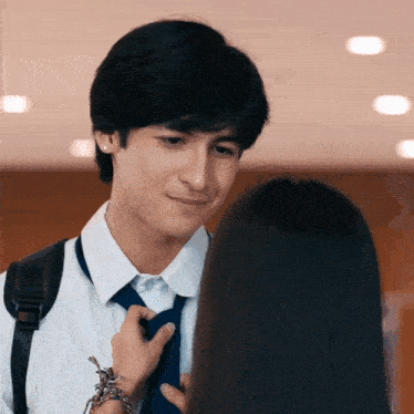 a man and a woman are looking at each other and the man is fixing the woman 's tie