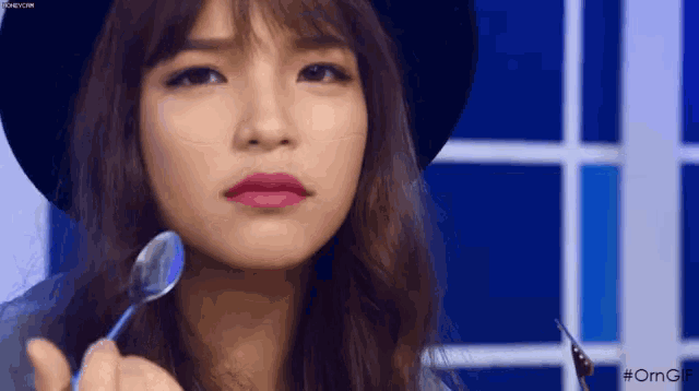 a woman is holding a spoon in her hand and making a funny face