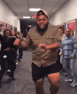 a group of people are dancing in a hallway with an exit sign visible