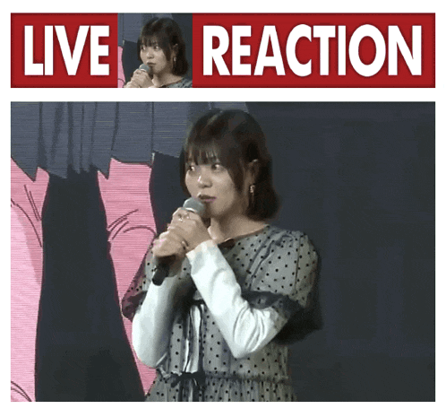 a woman is holding a microphone in front of a live reaction sign