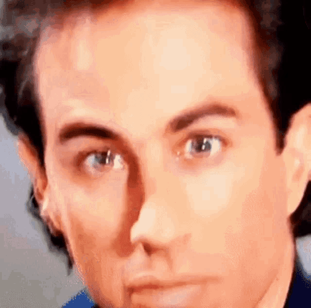 a close up of a man 's face with his eyes closed and a blue shirt on .