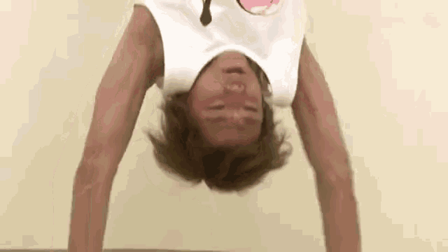 a man is doing a handstand upside down on a table with his eyes closed .