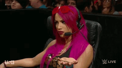 a woman with pink hair is sitting in a chair with a microphone on her head ..