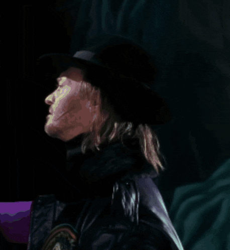 a man with long hair wearing a black hat and a purple jacket