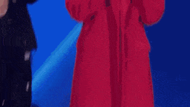 a woman in a red dress is dancing on a stage in front of a crowd .