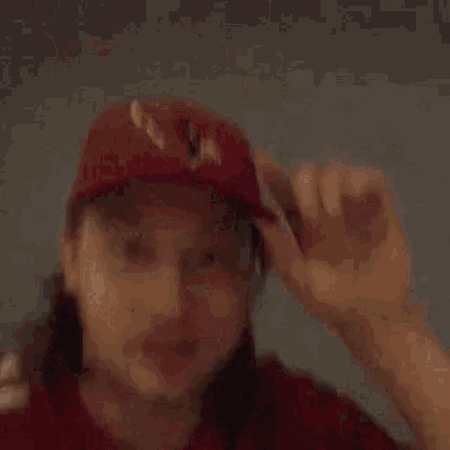 a man wearing a red cardinals jersey is standing in front of a white wall .
