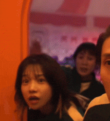 a group of people are standing in front of an orange wall looking at the camera .