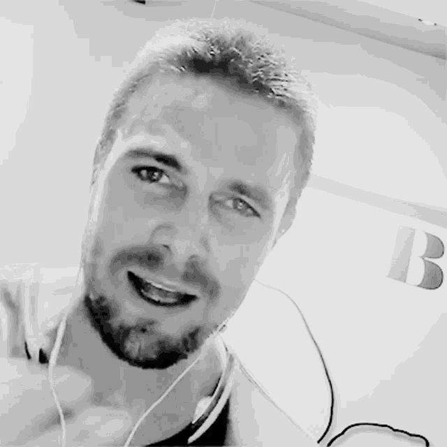 a black and white photo of a man with a beard wearing ear buds
