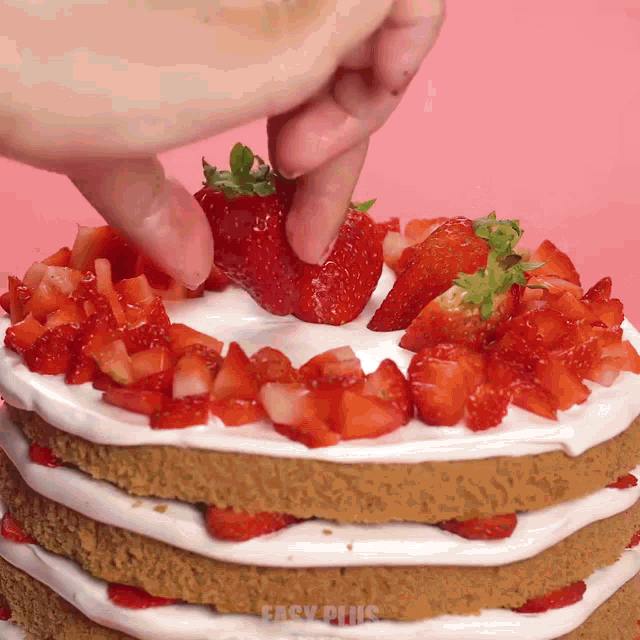 a person is putting strawberries on top of a cake that says easy plus on it