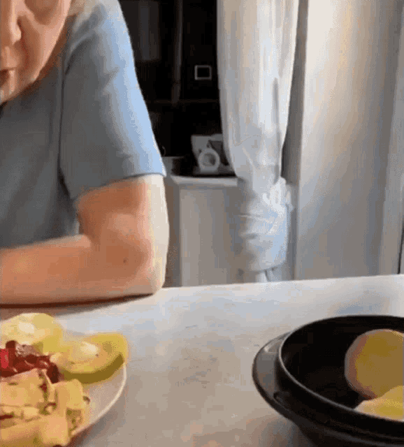 a person is sitting at a table with a plate of fruit on it