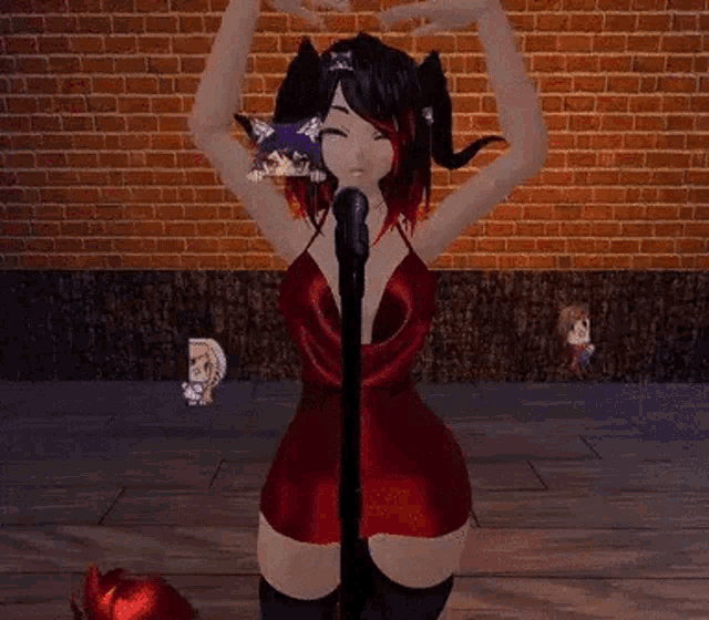 a girl in a red dress is standing in front of a microphone making a heart shape with her hands .
