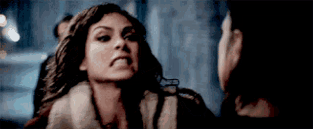a woman in a fur coat is making a funny face while talking to another woman .