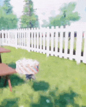 a white picket fence surrounds a picnic table in a backyard